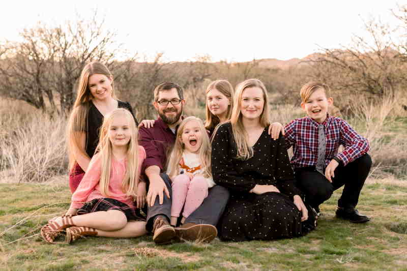 Family portrait of Dr. Joseph Larsen with his wife and five children outdoors in a natural setting, reflecting their love for family time and outdoor activities.